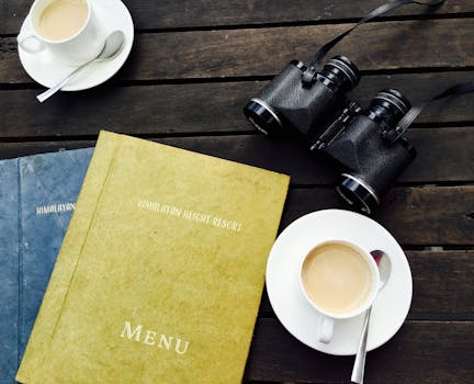A cozy coffee break at Himalayan Height Resort with menu and binoculars on a wooden table.